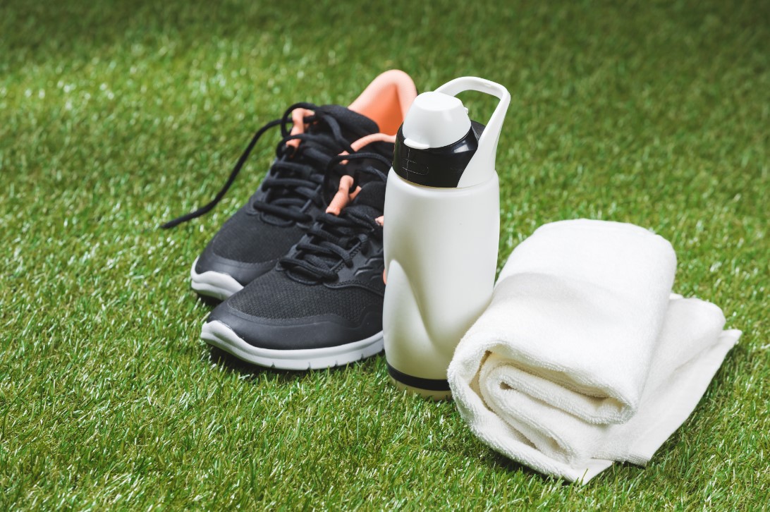 trainers, water bottle and towel on an outdoor pitch